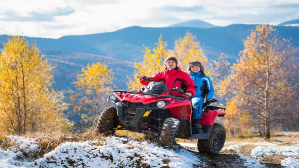 couple on a snow covered road riding an atv