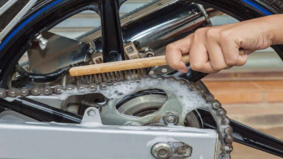 man cleaning sprocket and chains with a brush